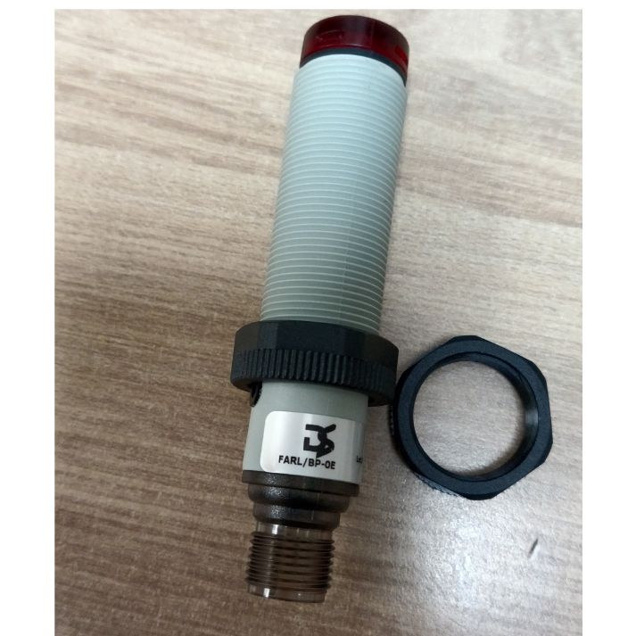Close-up of FARL/BP-0E industrial sensor with threaded connector and locking nut on wooden surface